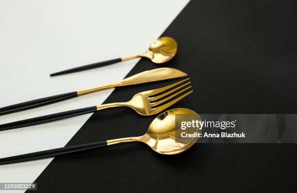 black and white diagonal paper background, black and golden cutlery flat lay. elegant dinner table setting. - colher talheres imagens e fotografias de stock