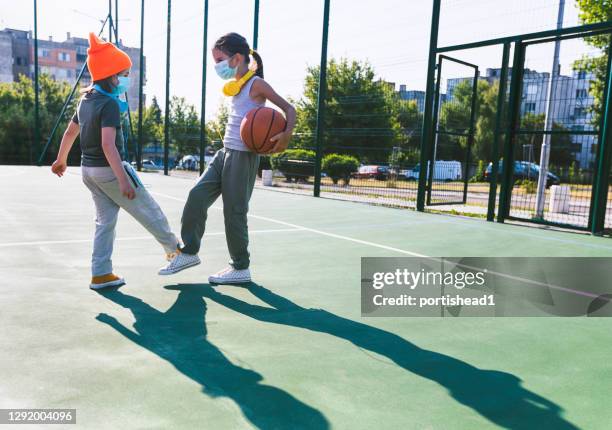 two children with face protective masks using foot bump. high five without hands - covid handshake stock pictures, royalty-free photos & images