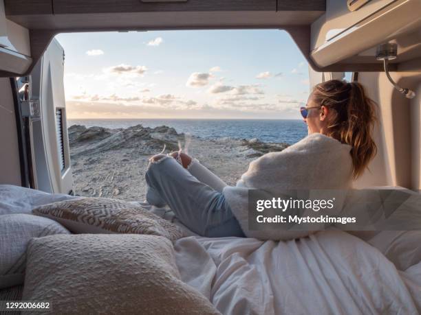 woman lying at the back of a van looking at ocean - road trip van stock pictures, royalty-free photos & images