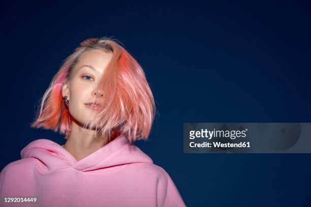 portrait of young woman with pink hair wearing pink hooded shirt at dusk - pink hair imagens e fotografias de stock