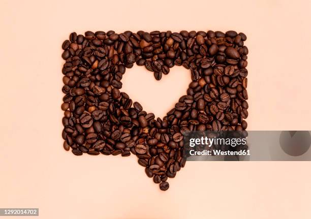 roasted coffee beans arranged into shape of heart inside online chat bubble - coffee heart fotografías e imágenes de stock