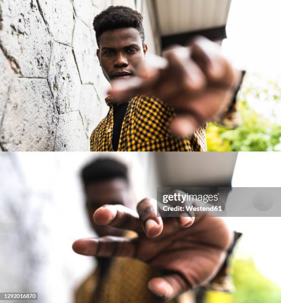 man stretching hand while standing by wall - attraper photos et images de collection