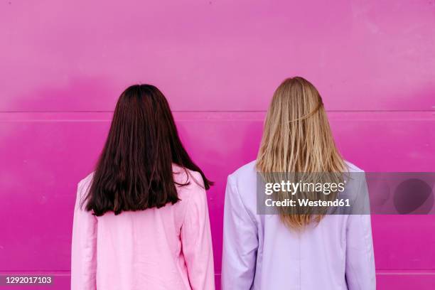 young sisters looking at pink wall - purple blazer stock pictures, royalty-free photos & images