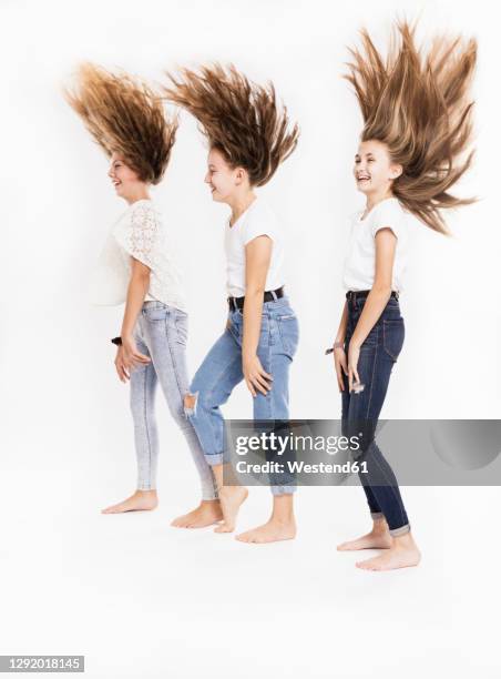 playful sisters tossing hair against white background - haare schütteln stock-fotos und bilder