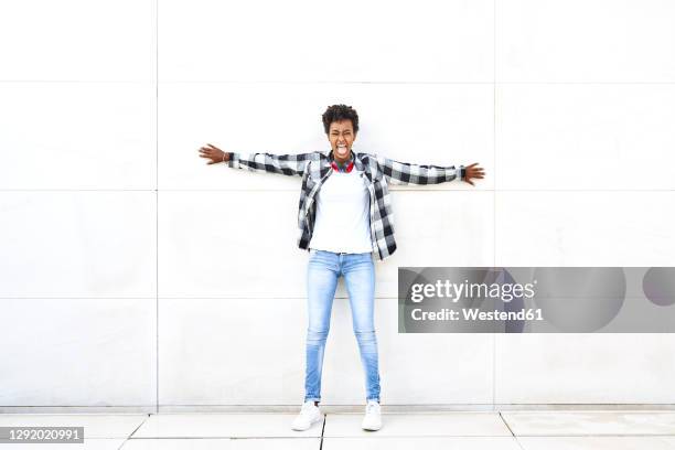 young female hipster shouting while standing with arms outstretched against white wall - vollständig aufgeknöpft stock-fotos und bilder