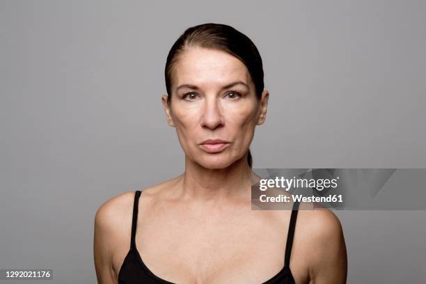 mature woman with slicked back hair against gray background - woman vest stock pictures, royalty-free photos & images