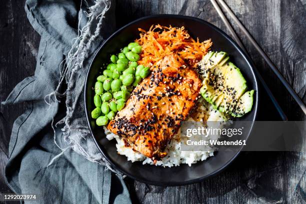 bowl ofteriyakisalmon with rice, carrot salad,edamamebeans, avocado and sesame seeds - zalm gerecht stockfoto's en -beelden