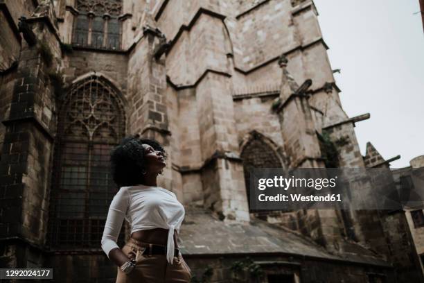 thoughtful woman looking up while standing against barcelona cathedral, barcelona, spain - barcelona cathedral stock pictures, royalty-free photos & images