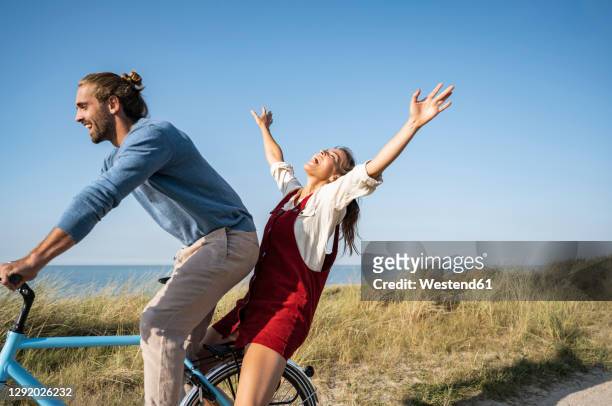 man and woman enjoying bicycle ride against clear sky - fahrrad paar stock-fotos und bilder