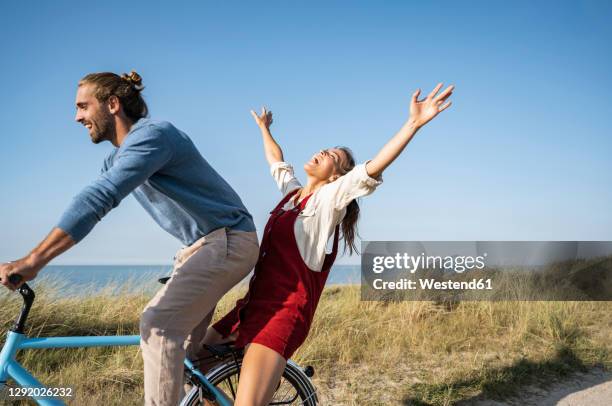 man and woman enjoying bicycle ride against clear sky - zondag stockfoto's en -beelden