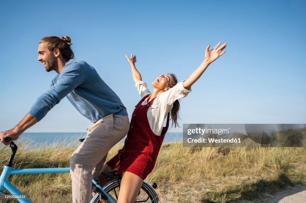 Man and woman enjoying bicycle ride against clear sky