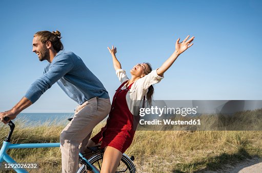 Man and woman enjoying bicycle ride against clear sky Man and woman enjoying bicycle ride against clear sky