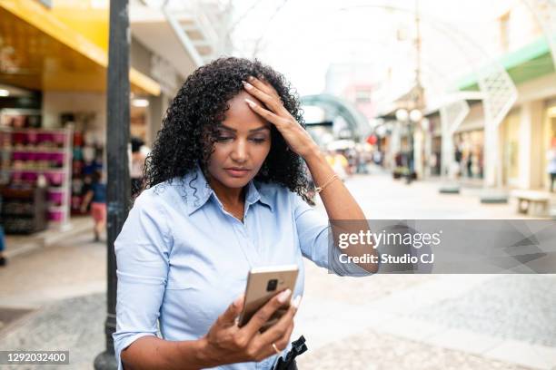 woman worried about news received on her cell phone. - computer virus stock pictures, royalty-free photos & images