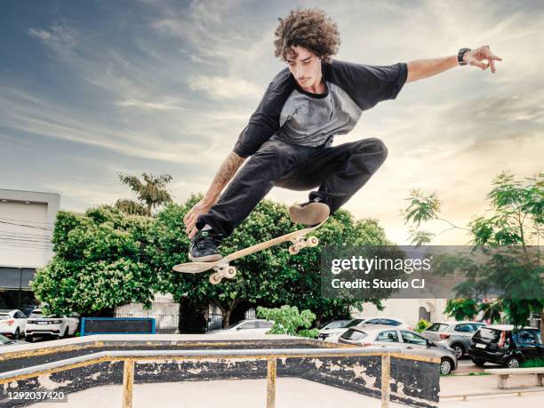 professional skateboarder performing maneuver in the air on urban track - stunt stock pictures, royalty-free photos & images