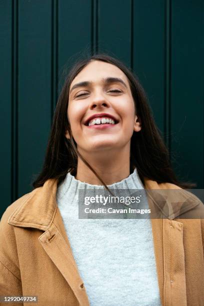 portrait of a young brunette woman smiling with eyes closed - woman teeth stock-fotos und bilder