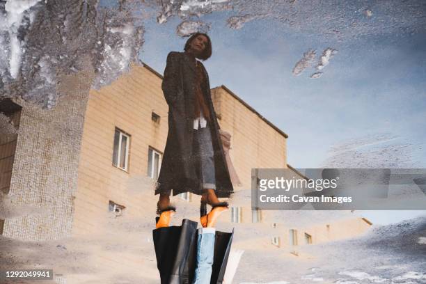 reflection of a woman posing in front of generic building, full - puddles stock-fotos und bilder