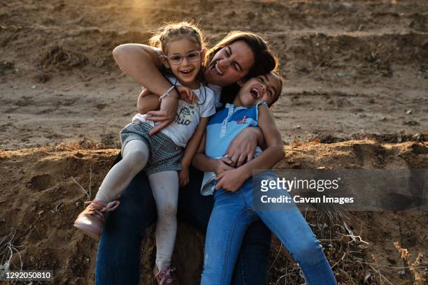 a mother sitting on the field plays with her daughters - refugee silhouette stock pictures, royalty-free photos & images