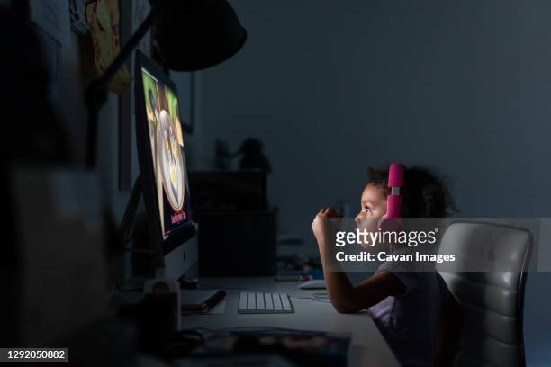 young girl with headphones using computer at home - nur mädchen stock-fotos und bilder