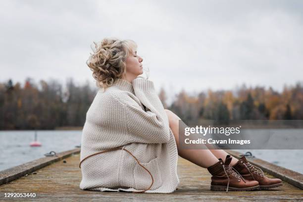 woman sat outside breathing in the fresh air looking thoughtful - fresh air breathing stockfoto's en -beelden