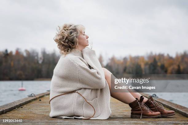 woman sat outside breathing in the fresh air looking thoughtful - deep breathing stock pictures, royalty-free photos & images