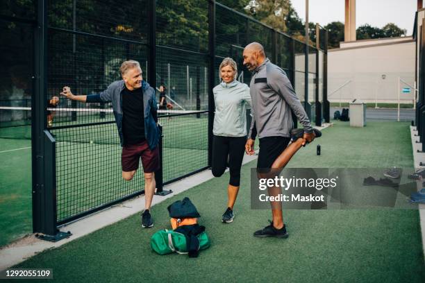 male and female friends stretching by net in sports court - court notice bildbanksfoton och bilder