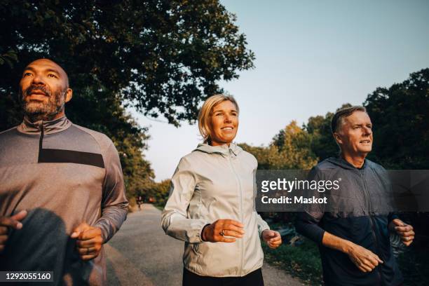 smiling female with friends looking away while jogging in park during sunset - black and white photo out door sport photos et images de collection