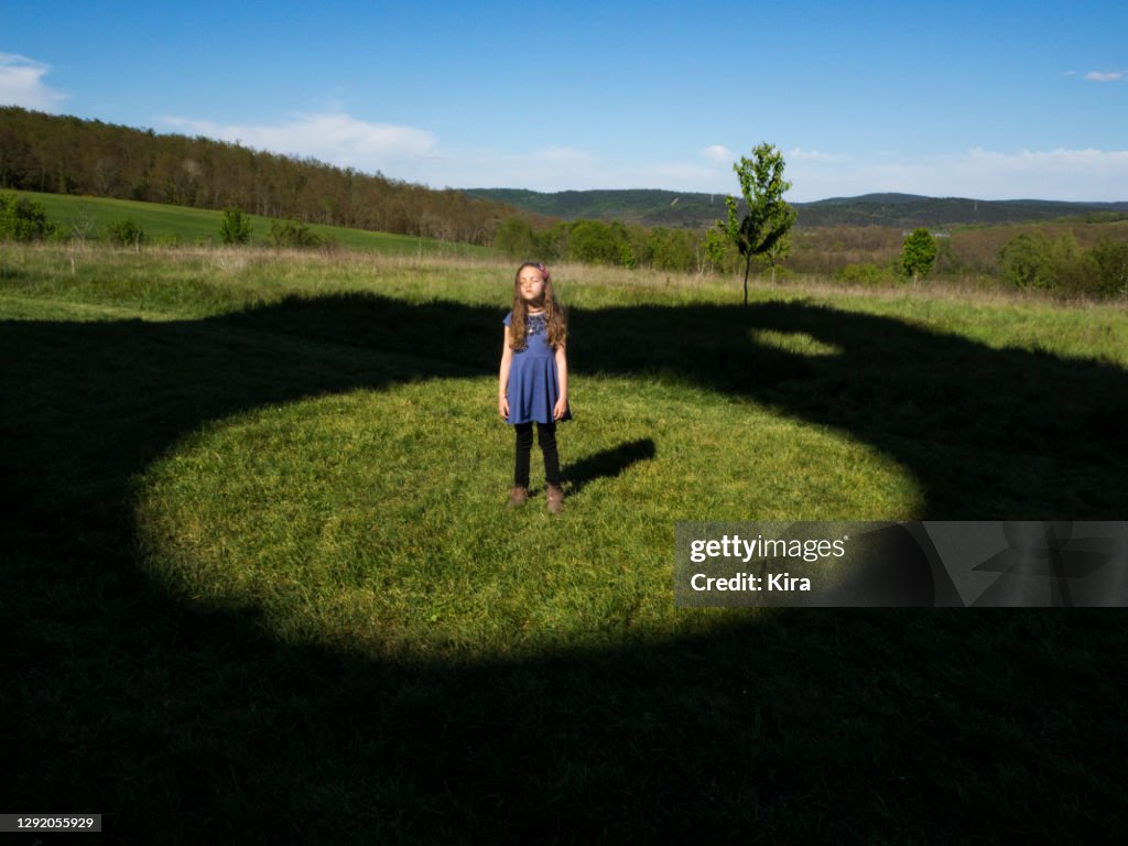 Girl standing in a field in the middle of a circle, Italy