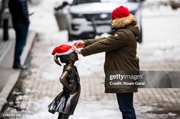Person places a Santa hat on the Fearless Girl statue outside the New York Stock Exchange in Wall Street as the city continues the re-opening efforts...