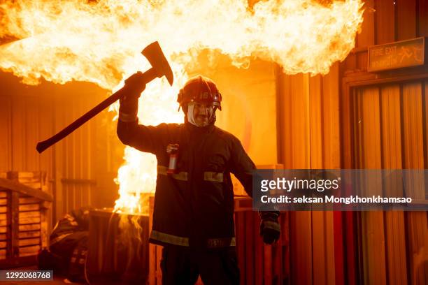 firefighters fighting a fire operation, fireman holding ax, firefighters extinguish burning warehouse - fireman axe stock pictures, royalty-free photos & images