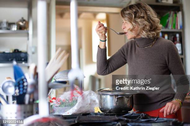 woman making a hearty soup, tasting from spoon - soup stock pictures, royalty-free photos & images