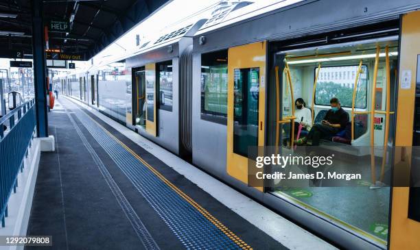 An empty station at Milsons Point with passengers on a train wearing face masks as residents of Greater Sydney are asked to consider staying at home...