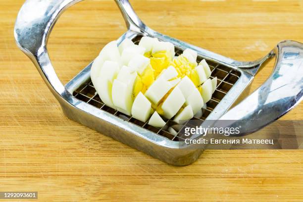 chicken egg slicing with cutter metal on used bamboo wooden chopping board background - hard boiled eggs stock-fotos und bilder