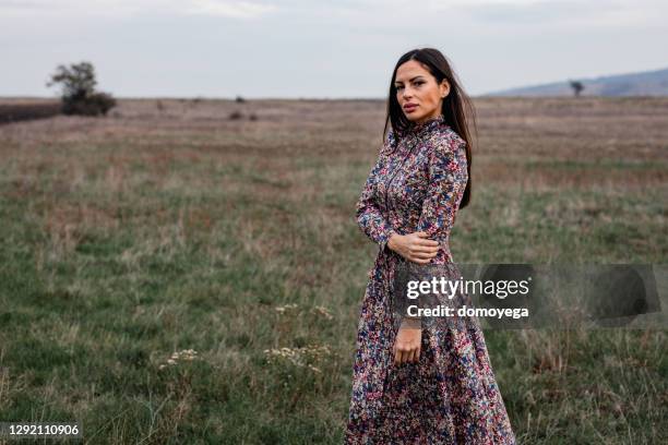 woman wearing a floral pattern dress on an autumn day in nature - long dress stock pictures, royalty-free photos & images