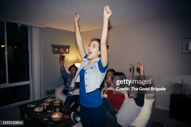 friends cheering while watching sports on tv at home - sports fan stockfoto's en -beelden