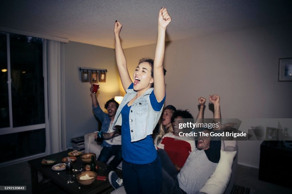 Friends cheering while watching sports on TV at home