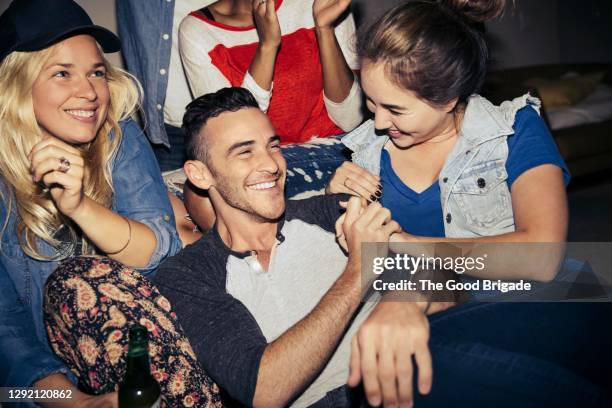 smiling male and female friends enjoying party at home - man met een groep vrouwen stockfoto's en -beelden