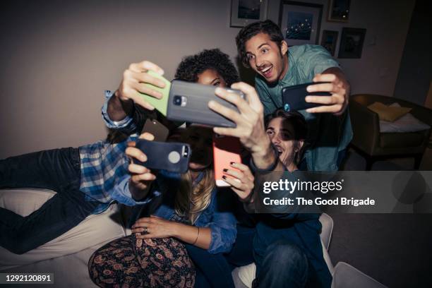 male and female friends taking selfie at home during party - millennials at party photos et images de collection