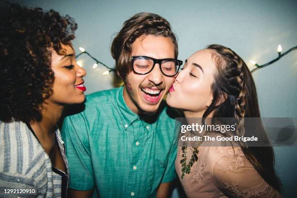 happy man enjoying kiss on cheek from female friend at home during party - horn rimmed glasses fotografías e imágenes de stock