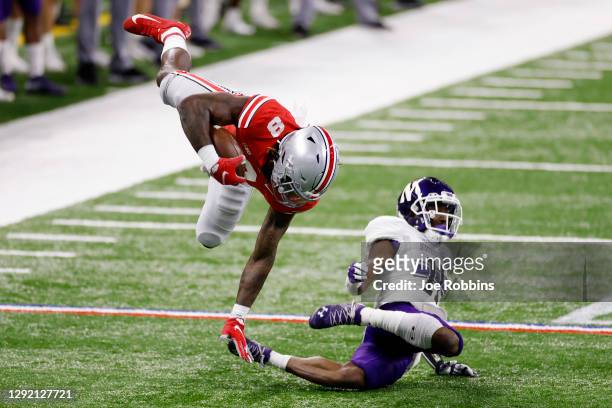 Trey Sermon of the Ohio State Buckeyes gets upended by A.J. Hampton of the Northwestern Wildcats in the first quarter of the Big Ten Championship at...