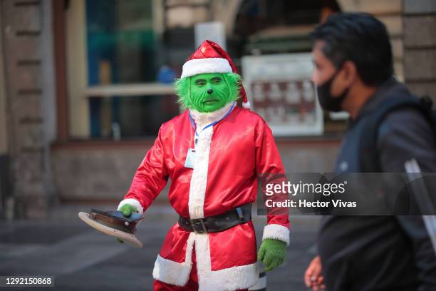 An organ grinder dressed as a Grinch asks for money in the streets of downtown Mexico City on December 19, 2020 in Mexico City, Mexico. Claudia...