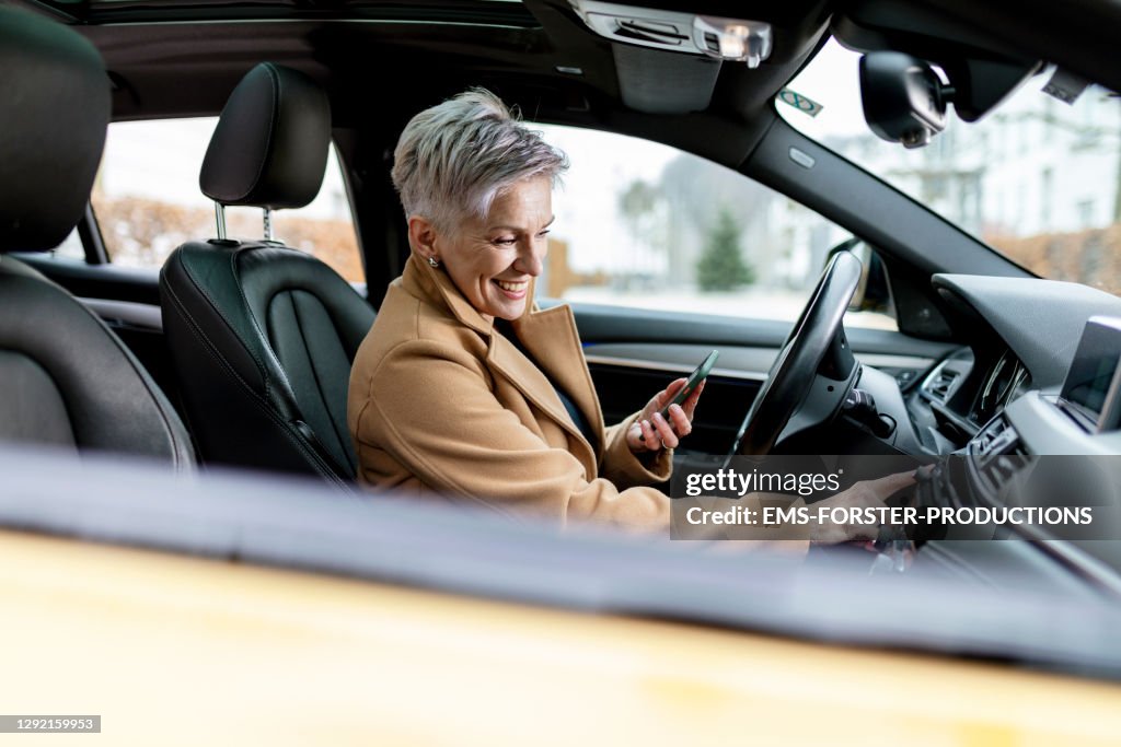 Active bestager women is using smart phone to start a sharing car