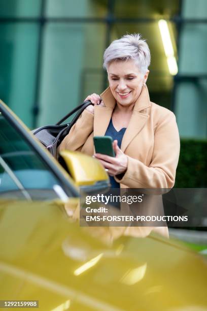 beautiful bestager women is using smart phone to unlock a rental car - carsharing - management car smartphone stock pictures, royalty-free photos & images