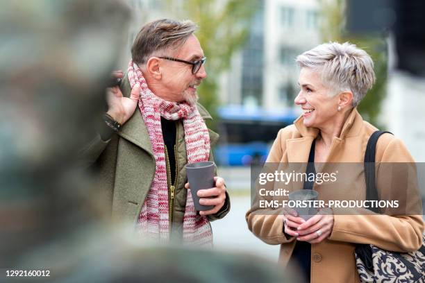 senior couple enjoying coffee to go and talking - flirting stockfoto's en -beelden