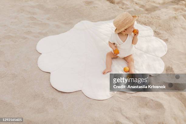 cute baby girl resting on sand by the sea. - zonnehoed stockfoto's en -beelden