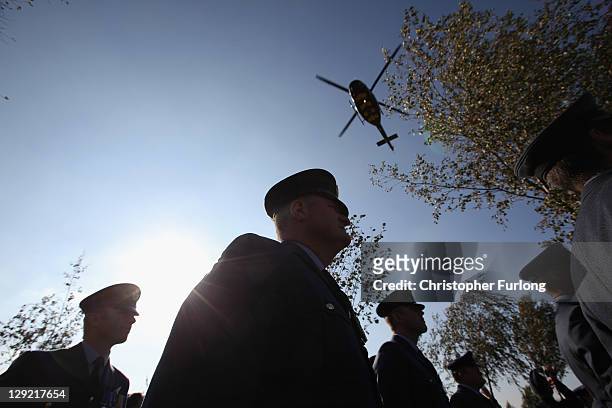 Members of the Royal Air Force Load Master Association watch as helicopters fly above them as a memorial stone is dedicated at the National Memorial...