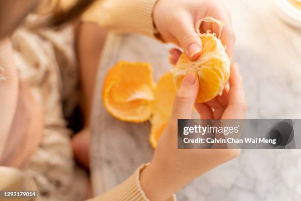 peeling mandarin orange on chinese new year - tangerine stock pictures, royalty-free photos & images