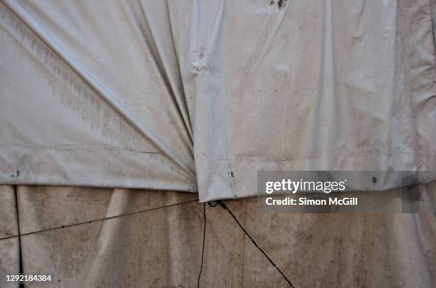 dirty white waterproof plastic tarpaulins, tied with ropes, covering an object - protective sheet stock pictures, royalty-free photos & images