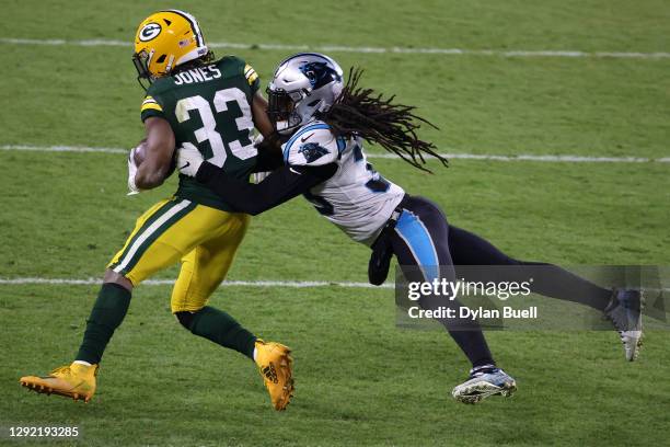 Running back Aaron Jones of the Green Bay Packers is tackled by free safety Tre Boston of the Carolina Panthers during the game at Lambeau Field on...