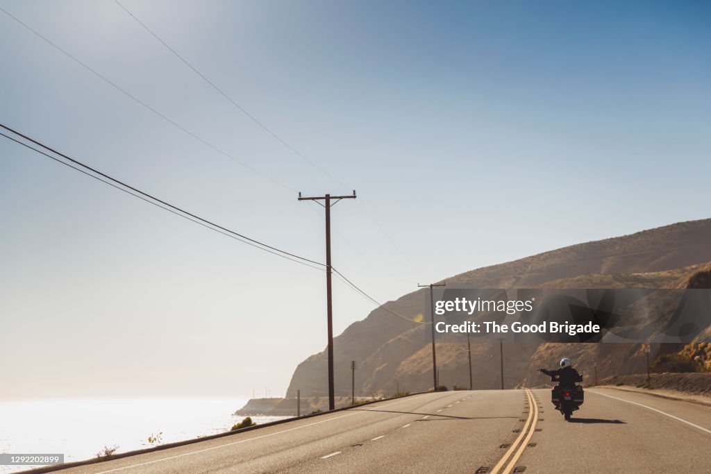 Couple riding motorcycle on coastal highway during sunny day