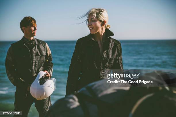 smiling woman with boyfriend against sea - crash helmet stock pictures, royalty-free photos & images